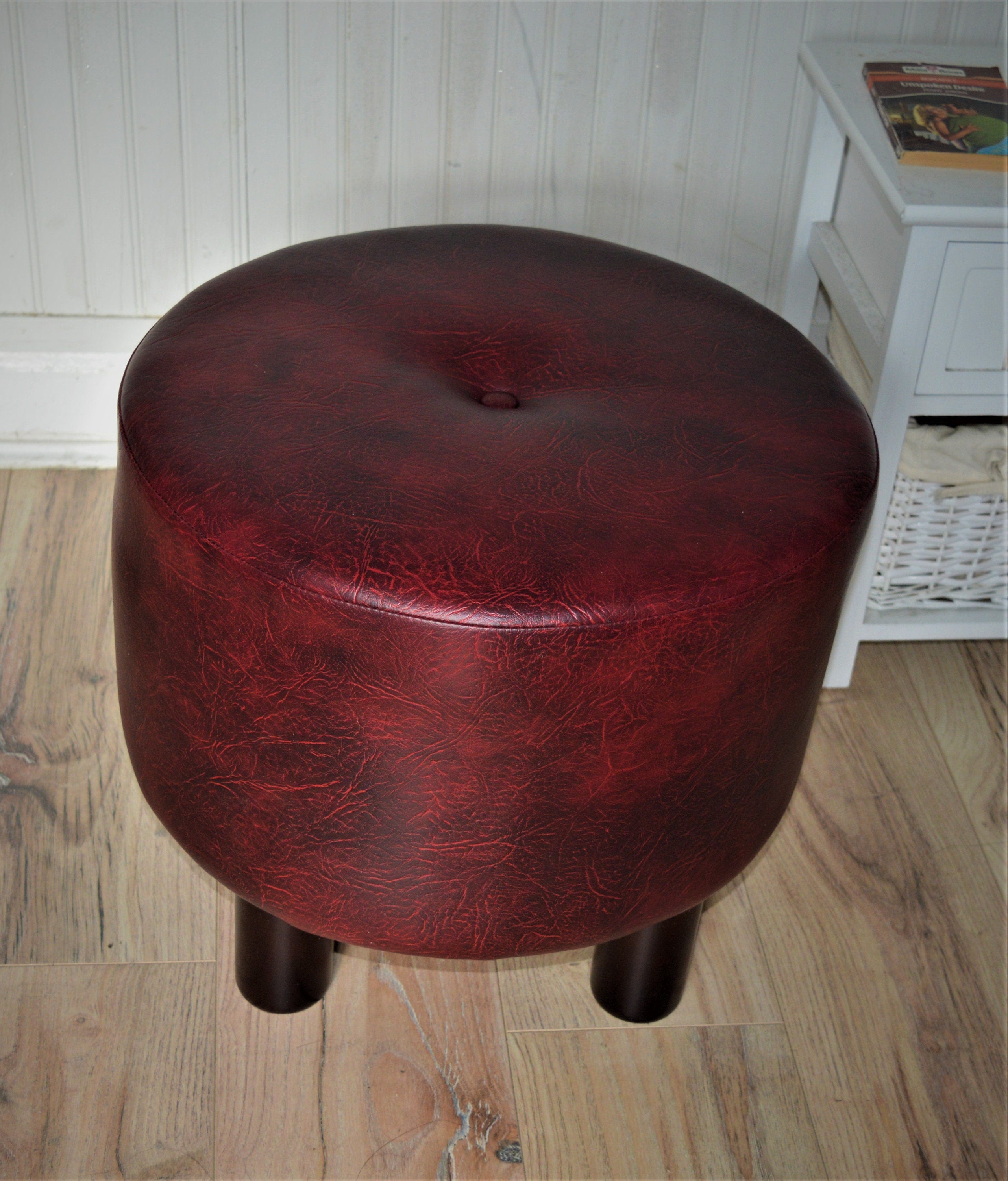 Circular round footstool upholstered in a premium wine faux leather with 4 cylinder Hard Wood Legs