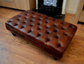 A Stylish UK Made Deep Buttoned Chesterfield Footstool in Premium Chestnut Faux Leather With Turned Hardwood Legs